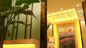Eine Hotellobby mit einer großen Kübelpflanze, einem gerahmten Gemälde eines Feldes und einer modernen Chandelier.
