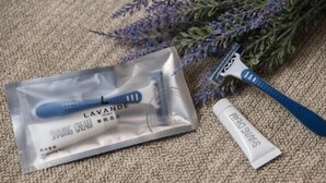 A shaving kit with a razor and shaving cream, placed on a textured surface with a lavender plant in the background. - Lavande Hotel (Zhuanghe Xiangyang Road) (Zhuanghe)