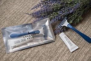 A shaving kit with a razor and shaving cream, placed on a textured surface with a lavender plant in the background. - Lavande Hotel (Zhuanghe Xiangyang Road) (Zhuanghe)