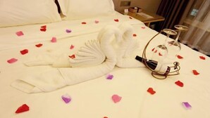Ein Hotelzimmer mit einem ordentlich bezogenen Bett, einem Satz Weingläser und einem kleinen Tisch mit einer Lampe.