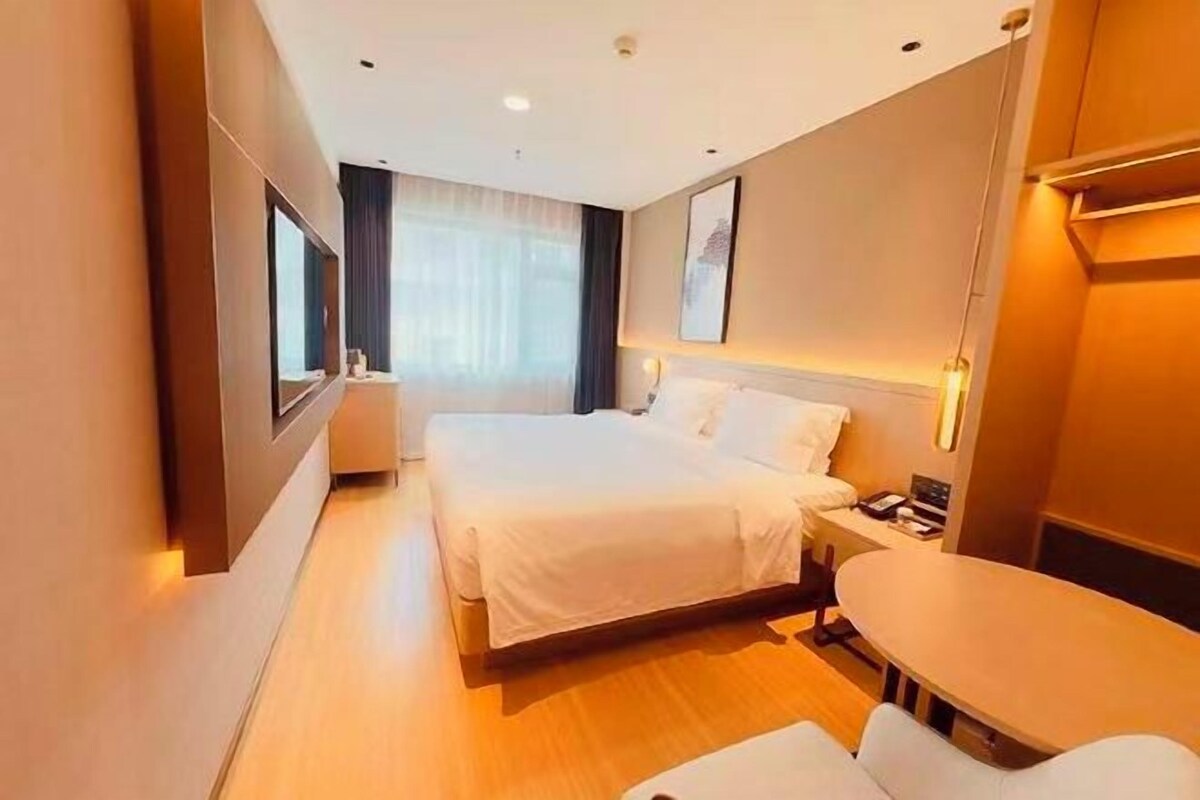 A hotel room with a bed, bedside table, and a desk.