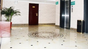 A clean, modern lobby with a marble floor, a reception desk, a potted plant, and two elevators. - Greentree Alliance Gansu Longnan Beishan East Road Hotel (Longnan)