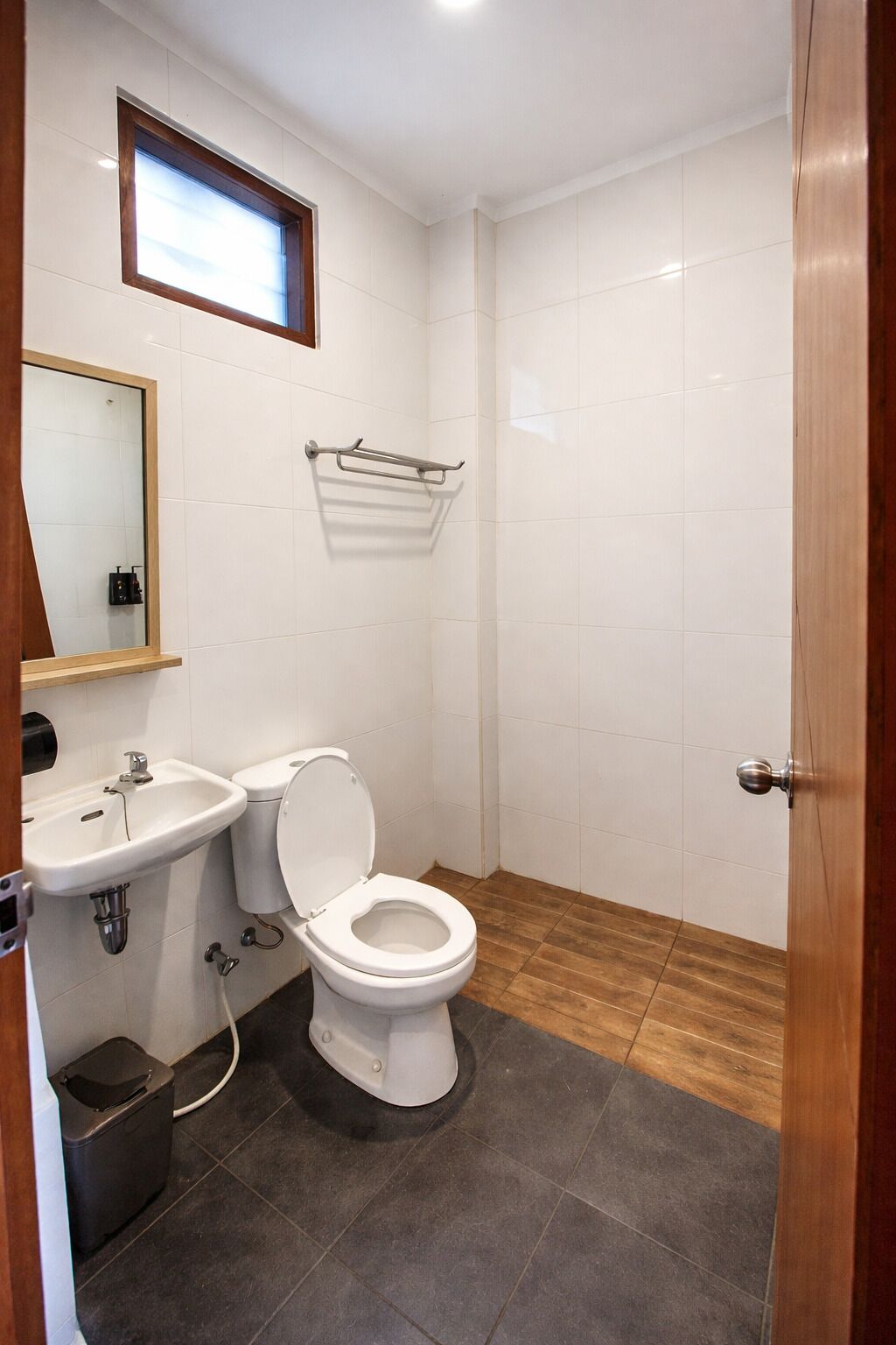 A bathroom with a toilet, sink, and a window.