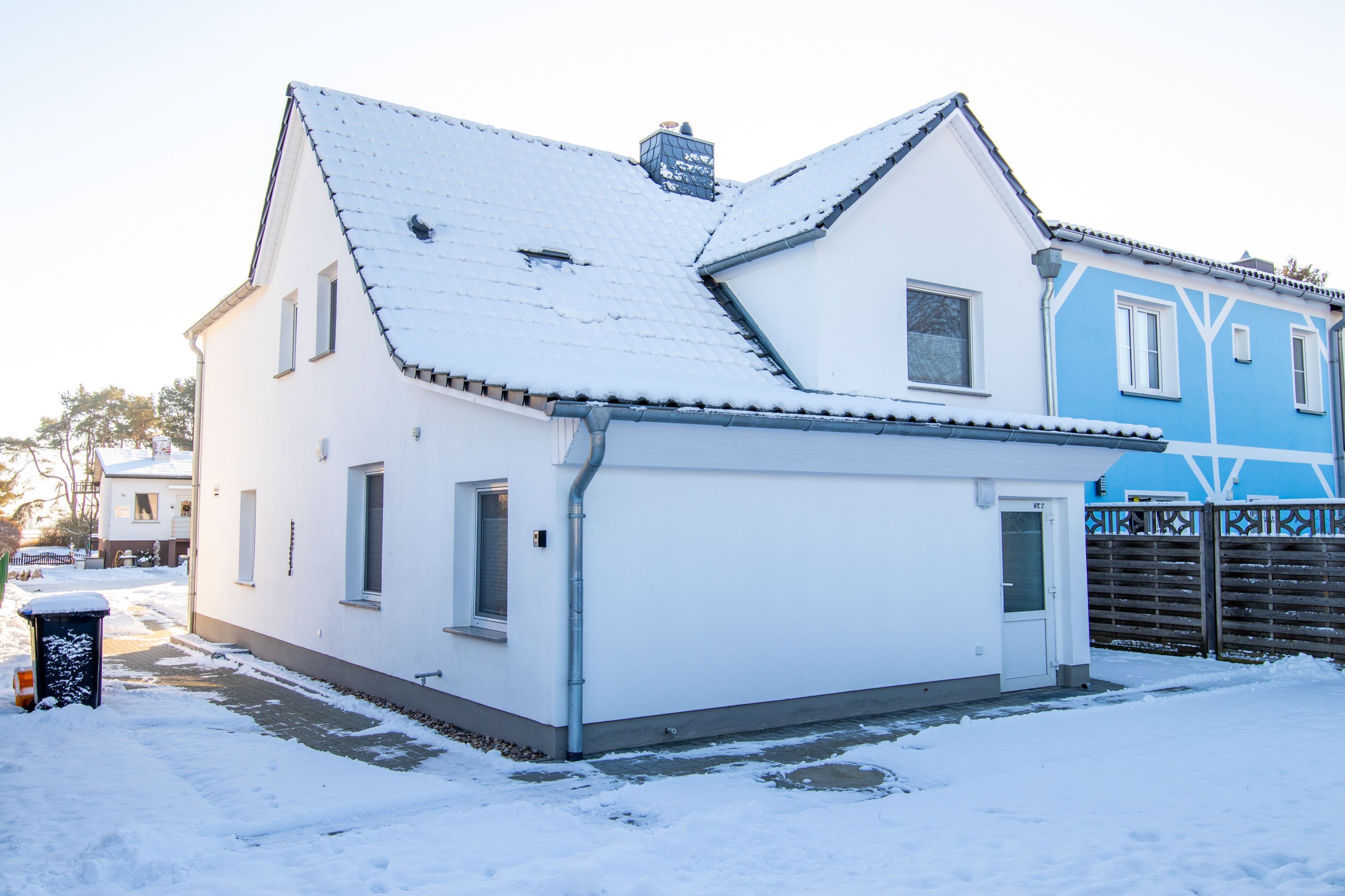 A two-story house with a snow-covered roof, a garage, and a fenced yard.