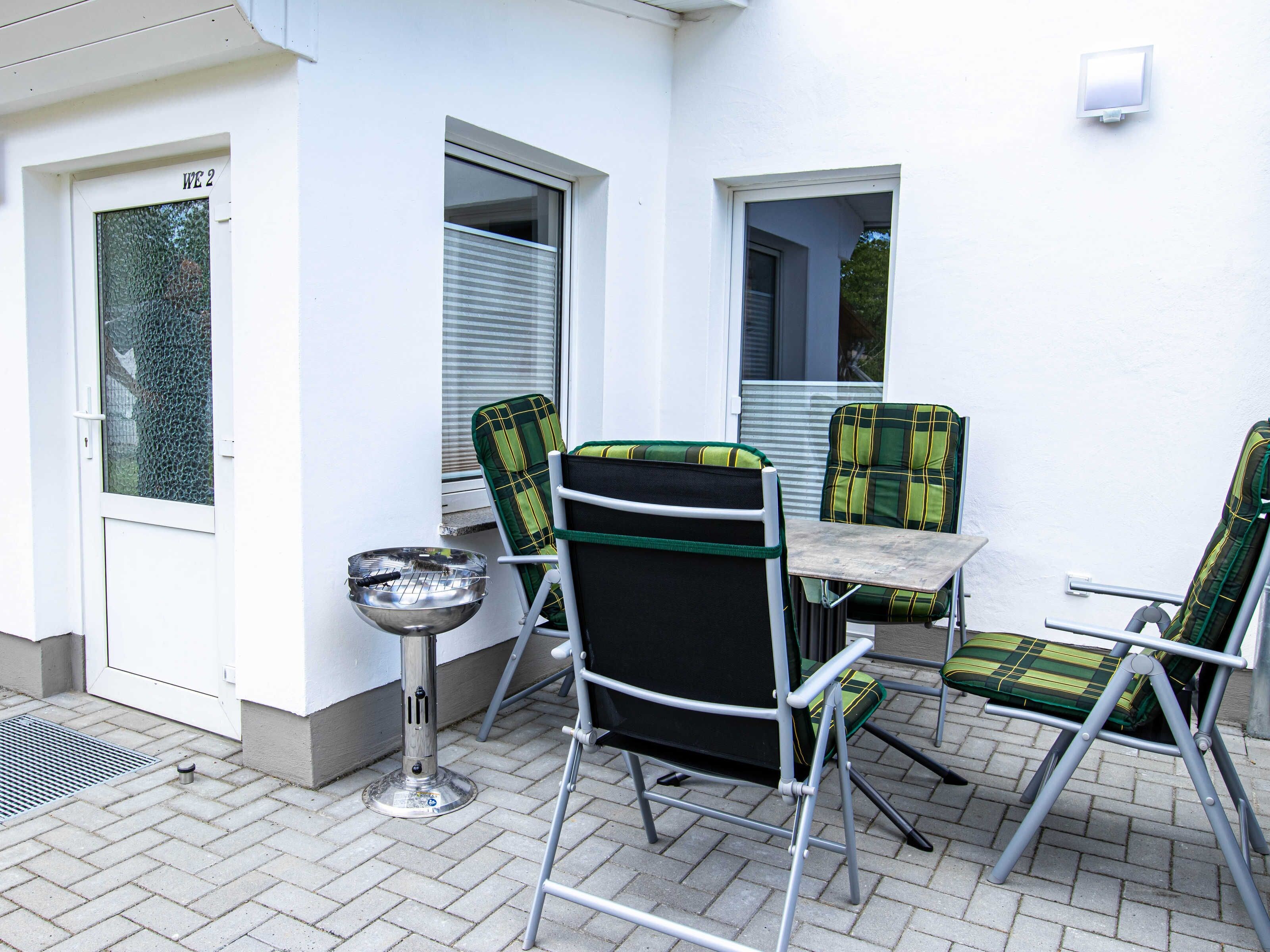 A patio with a table and chairs, a metal stool, and a door with a window.