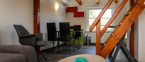 A modern interior with a staircase, seating area, and a view of the outdoors.