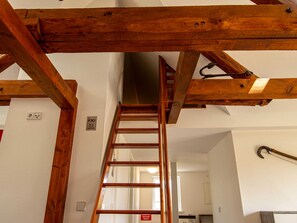 Un escalier en bois avec une rampe, un panneau indiquant une zone non-fumeur et une porte en bas.