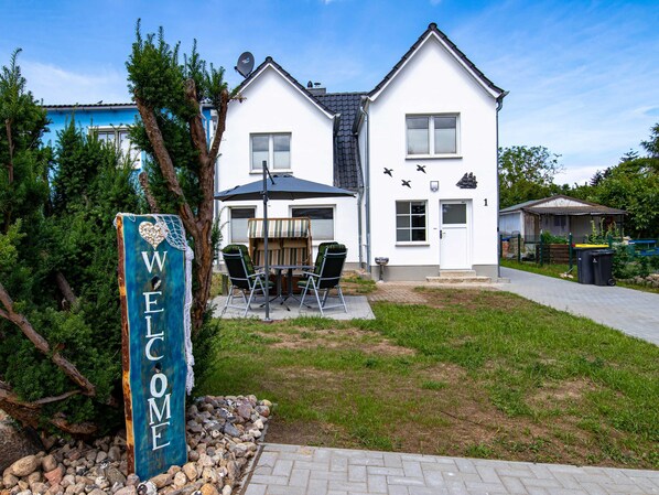 A two-story house with a patio, a welcome sign, and a satellite dish.