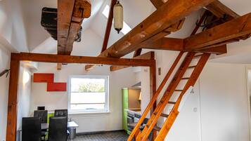 Una stanza con travi a vista in legno, un'area pranzo con sedie e tavolo, una finestra con vista e un angolo cottura con elettrodomestici.