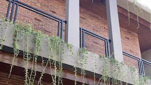 A building with a brick facade, white columns, and a balcony with climbing plants. - Amarilis near Sam Poo Kong (Semarang)