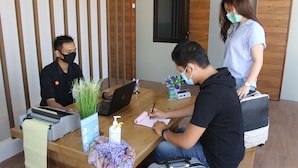 A reception desk with a laptop, a notepad, and a pen. There is a plant and a bottle of hand sanitizer on the desk. - Amarilis near Sam Poo Kong (Semarang)