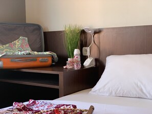 A hotel room with a bed, a nightstand with a lamp, a power outlet, and a suitcase on the bed. - Amarilis near Sam Poo Kong (Semarang)