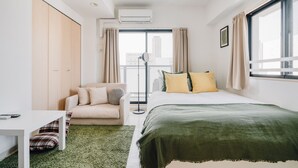 Habitación de hotel moderna con cama, sofá, una mesita y ventana con cortinas.