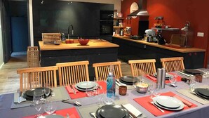 Una cocina moderna con una isla central, sillas de madera y una mesa de comedor para seis personas.