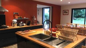 Una cocina moderna con una isla grande, pileta doble y un comedor con sillas de madera.