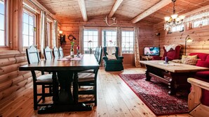 A wooden cabin interior with a dining area, a living room with a red sofa, and a television. - Lovely home in østby with house a mountain view (Østby)