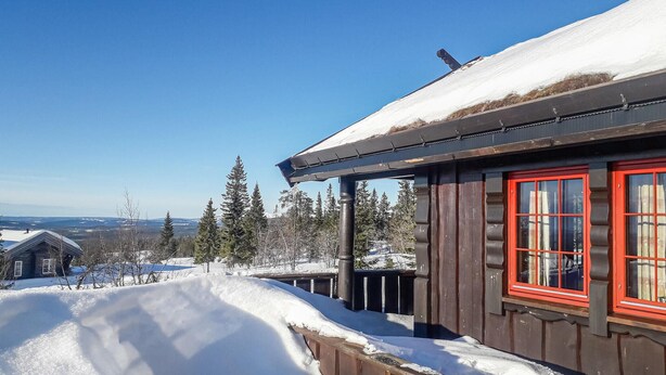 A wooden cabin with a red window, surrounded by snow-covered landscape and trees. - Lovely home in østby with house a mountain view (Østby)