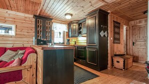A cozy cabin interior with a wooden interior, a kitchen area, and a seating area with a red sofa. - Lovely home in østby with house a mountain view (Østby)