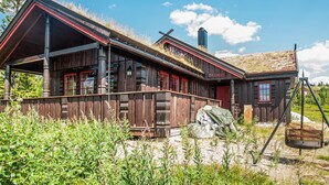 A rustic wooden building with a sloped roof, a sign reading "SKOGHEIM," and a swing set in the foreground. - Lovely home in østby with house a mountain view (Østby)