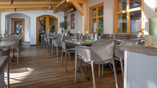 A restaurant with wooden floors, metal chairs, and tables. - Das kleine Hotel (Stumm)