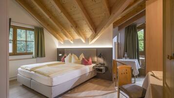 Un dormitorio con cama, mesita de noche, lámpara y una pequeña mesa con una silla.