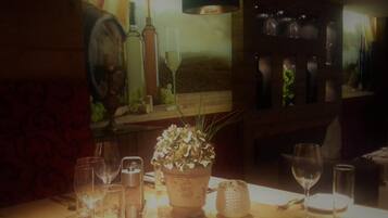 Una mesa con copas de vino, una botella y una planta en maceta en una habitación con poca luz y decoración de madera.
