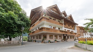 A multi-story building with wooden balconies, a street in front, and a clear sky. - Das kleine Hotel (Stumm)