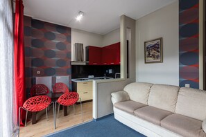 A compact living space with a kitchenette, a dining area with red chairs, and a sofa. - VIP-Aparts Bukovel (Bukovel)