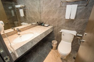 Un baño moderno con lavamanos de mármol, ducha con cerramiento de vidrio y un inodoro.