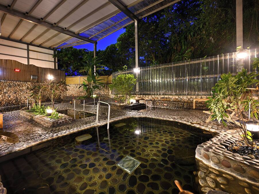 A heated outdoor pool with stone steps and railings, surrounded by plants and a stone wall.