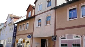 Un edificio a più piani con un cartello per 'KRAM Kunst' e un negozio 'Korzen'.