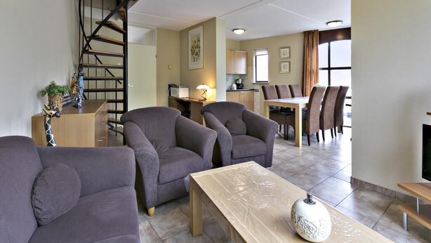 A living room with a sofa, armchairs, a coffee table, and a staircase. - Holiday house "White Shell" - large garden - parking lot directly at the house  (Brouwershaven)