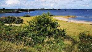 A coastal landscape with a grassy area, a dock, and boats on the water. - Holiday house "White Shell" - large garden - parking lot directly at the house  (Brouwershaven)