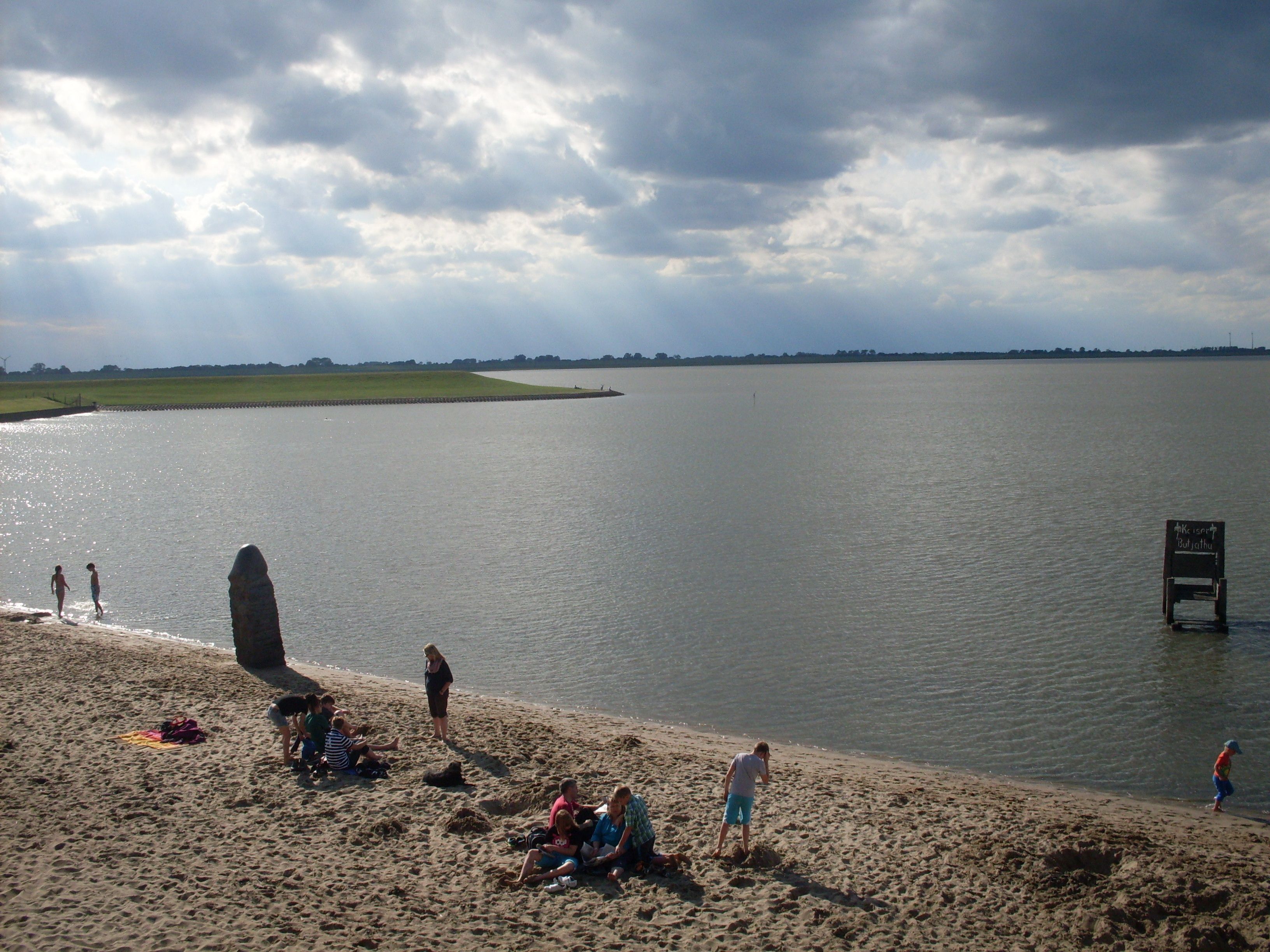 Ein Strand mit Menschen und einer großen Felsformation im Wasser.
