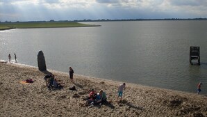 A beach with people and a large rock formation in the water. - Ferienhaus Newerenczuk, Vermietungsservice Dangast - Ferienhaus Newerenczuk (Varel)