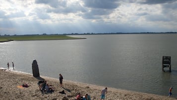 Ein Strand mit Menschen und einer großen Felsformation im Wasser.