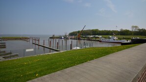 A marina with boats docked, a crane, and a grassy area with a pathway. - Ferienhaus Newerenczuk, Vermietungsservice Dangast - Ferienhaus Newerenczuk (Varel)