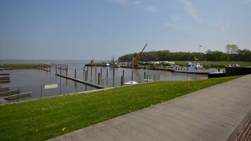 A marina with boats docked, a crane, and a grassy area with a pathway.