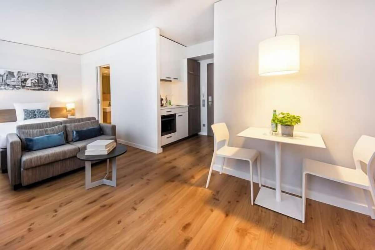 Ein modernes Wohnzimmer mit einer Couch, einem kleinen Tisch und einem Essbereich mit Stühlen.