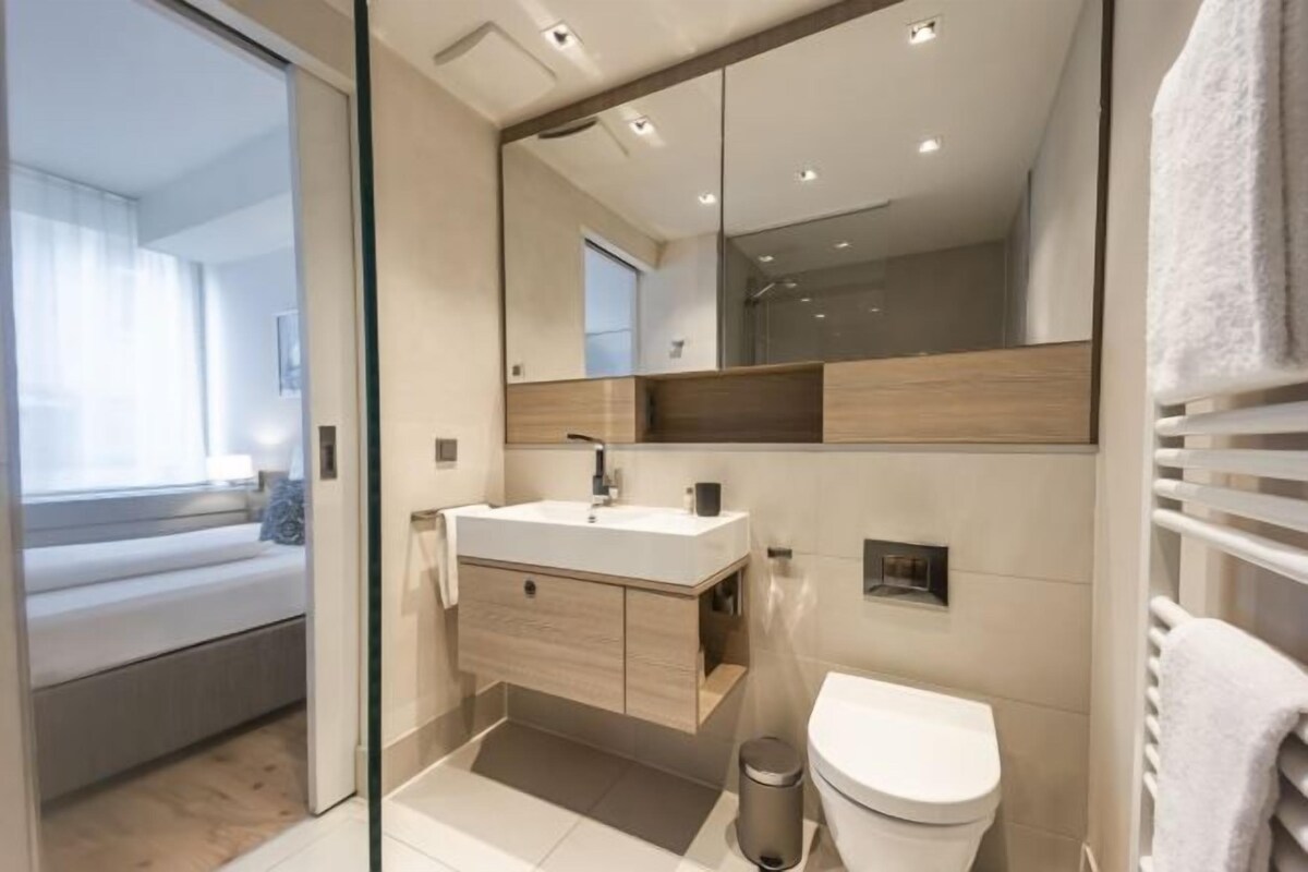 A modern bathroom with a glass shower enclosure, a white sink, and a toilet.