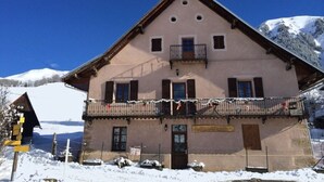 Ein traditionelles Chalet mit Balkon, einer Holztür und einem Schild.