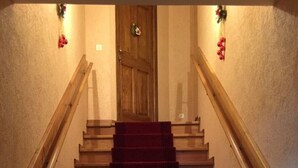 Eine Treppe mit rotem Teppich, hölzernen Handläufen und einer Tür am Obergeschoss.
