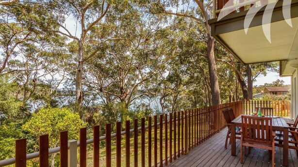 A wooden deck with a table and chairs, surrounded by a wooden fence and trees. - Lakeside Retreat @ Smiths Lake (Smiths Lake)
