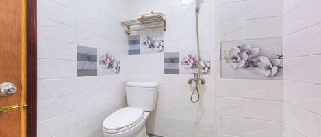 Un baño con azulejos blancos, un inodoro, una ducha y un perchero para toallas.