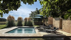 A swimming pool with a wooden deck, lounge chairs, and a pergola with a green umbrella. - Dominique and Eric welcome you to their large, characterful Mas with heated swimming pool. (Verquiéres)