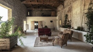 A spacious interior with a high ceiling, stone walls, and a mix of modern and vintage furniture. - Dominique and Eric welcome you to their large, characterful Mas with heated swimming pool. (Verquiéres)