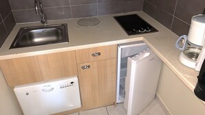Una cocina compacta equipada con lavamanos, estufa, lavavajillas y cafetera.