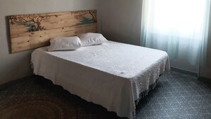 Ein Schlafzimmer mit hölzernem Kopfteil, weißer Bettdecke und einem gemusterten Teppich.