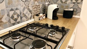 A kitchen with a gas stove, a coffee maker, and a microwave. - Mondello Beach Rooms (Palermo)