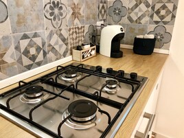 Uma cozinha equipada com fogão a gás, cafeteira e micro-ondas.